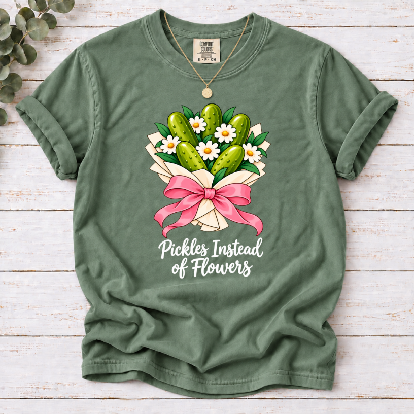Moss T-shirt with a pickle and daisy bouquet, pink bow, and white ‘Pickles Instead of Flowers’ lettering