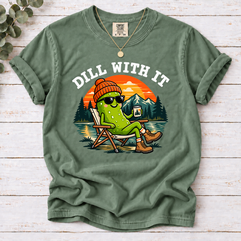 Moss Dill With It T-shirt featuring a pickle in sunglasses relaxing in a camp chair beside a lake at sunset.