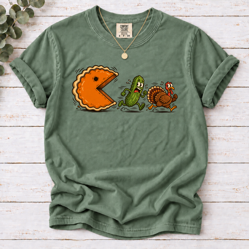 Moss T-shirt featuring a cartoon pumpkin pie chasing a frightened pickle and turkey.
