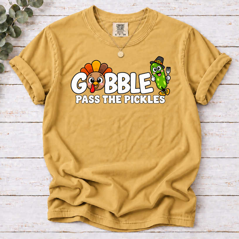 Mustard T-shirt with ‘Gobble Pass the Pickles’ lettering, a cartoon turkey and a pilgrim pickle holding a fork.