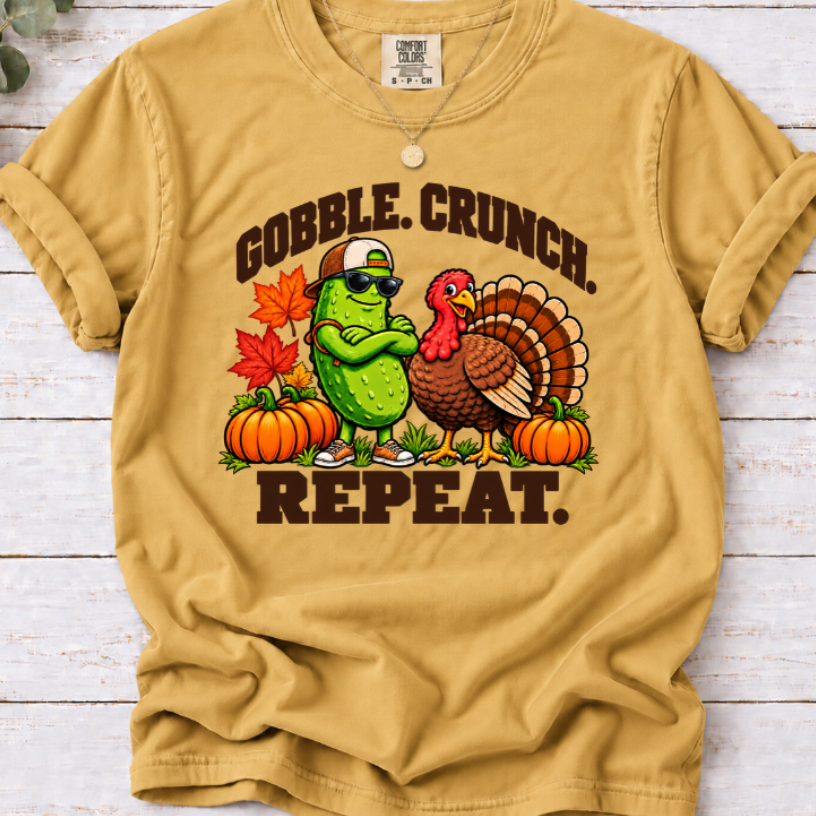 Mustard Gobble Crunch Repeat’ T-shirt featuring a sunglasses-wearing pickle beside a turkey, pumpkins, and fall leaves