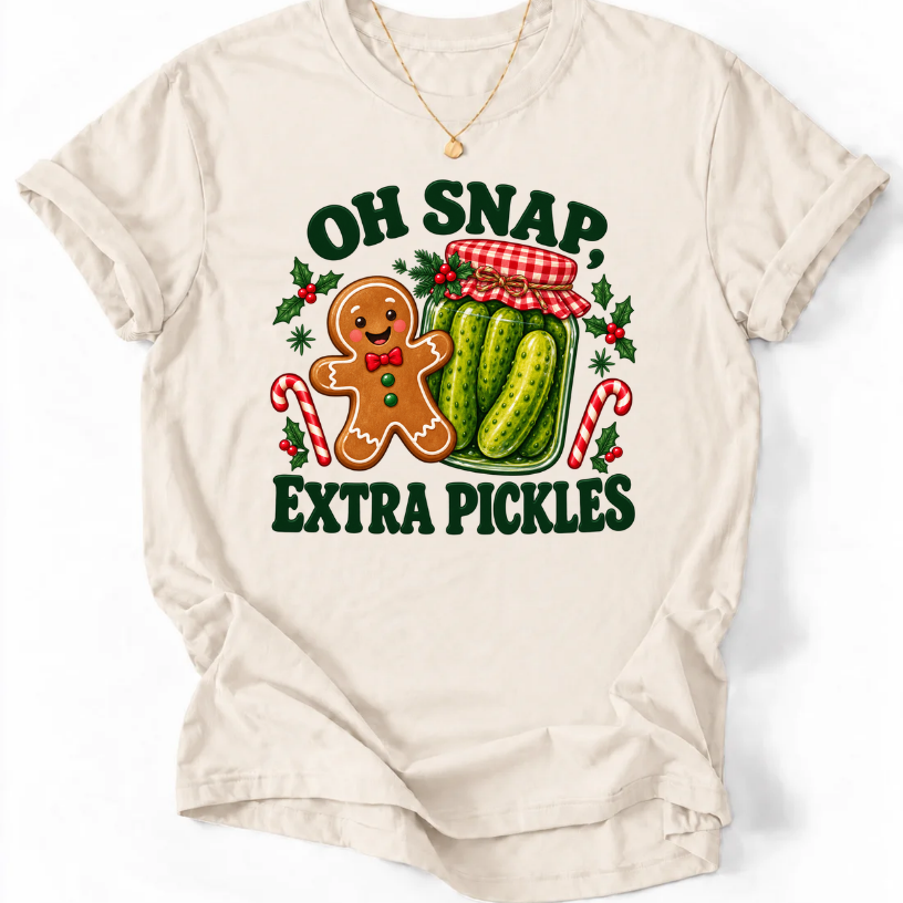 Natural T-shirt with “Oh Snap, Extra Pickles” lettering, a smiling gingerbread character, and a pickle jar surrounded by candy canes and holly.