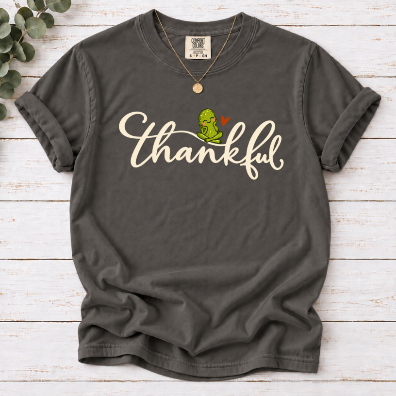 Pepper T-shirt with thankful script, a smiling green pickle, and a small orange heart.