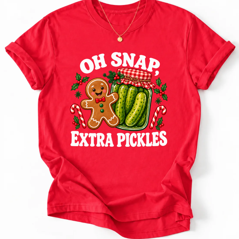 Red T-shirt with “Oh Snap, Extra Pickles” lettering, a smiling gingerbread character, and a pickle jar surrounded by candy canes and holly.