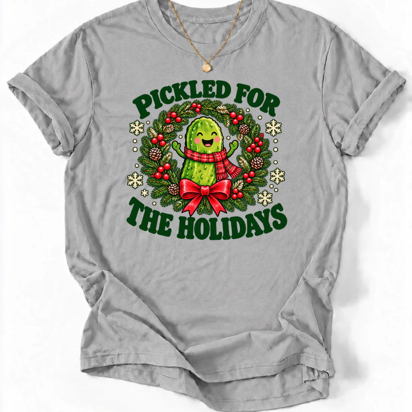 Sports Grey Pickled for the Holidays’ T-shirt with a smiling pickle in a red scarf inside a Christmas wreath.”