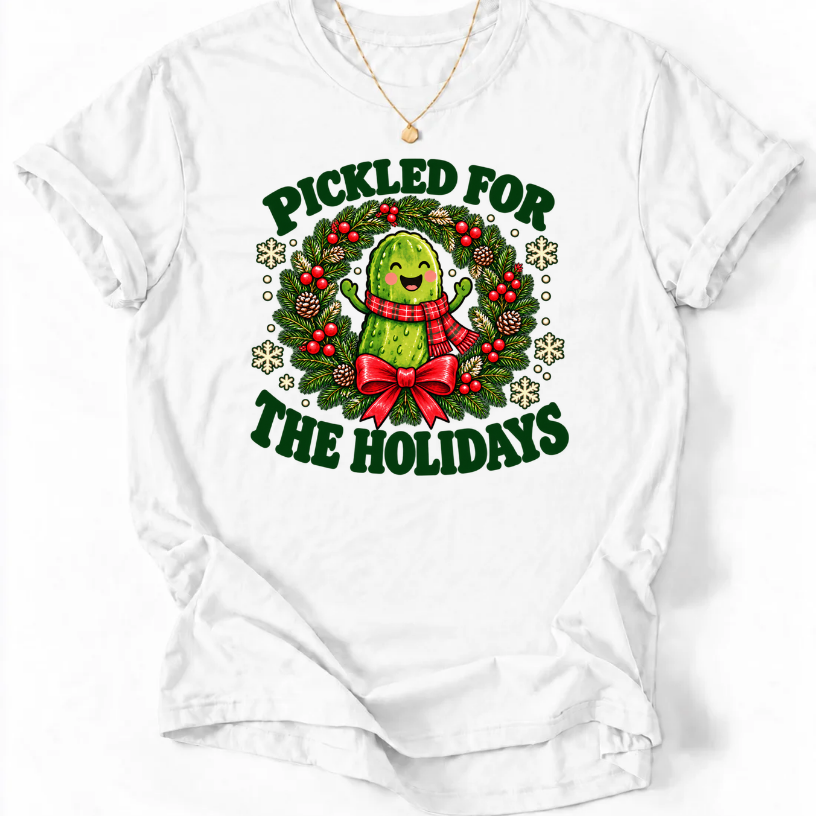 White Pickled for the Holidays’ T-shirt with a smiling pickle in a red scarf inside a Christmas wreath.”
