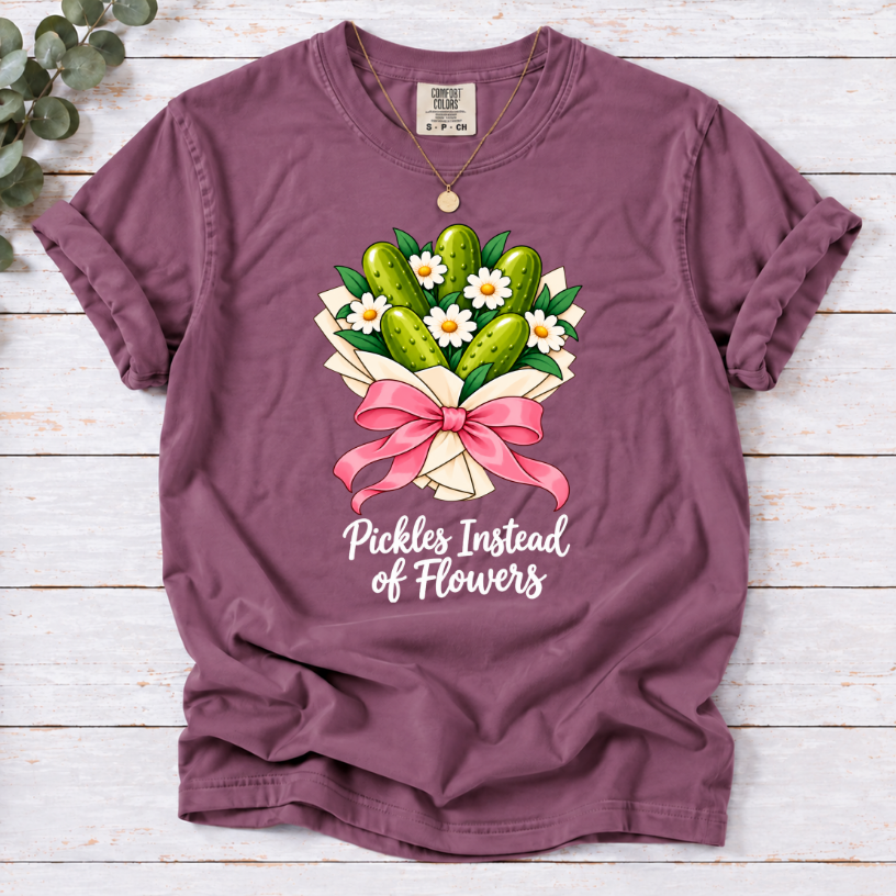 Berry T-shirt with a pickle and daisy bouquet, pink bow, and white ‘Pickles Instead of Flowers’ lettering