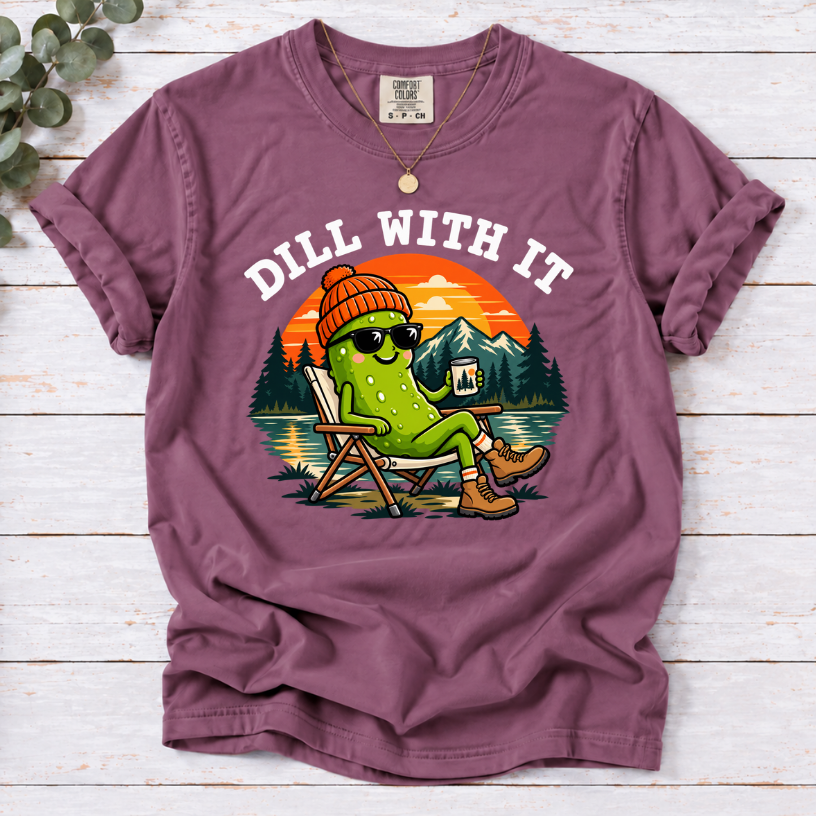 Berry Dill With It T-shirt featuring a pickle in sunglasses relaxing in a camp chair beside a lake at sunset.