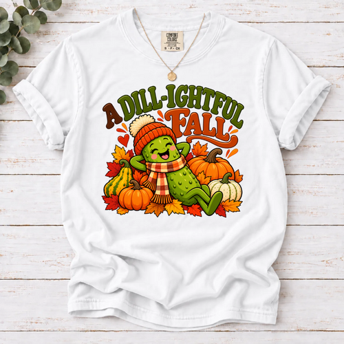 White A Dill-ightful Fall T-shirt with a smiling pickle in a beanie and plaid scarf among pumpkins and autumn leaves.